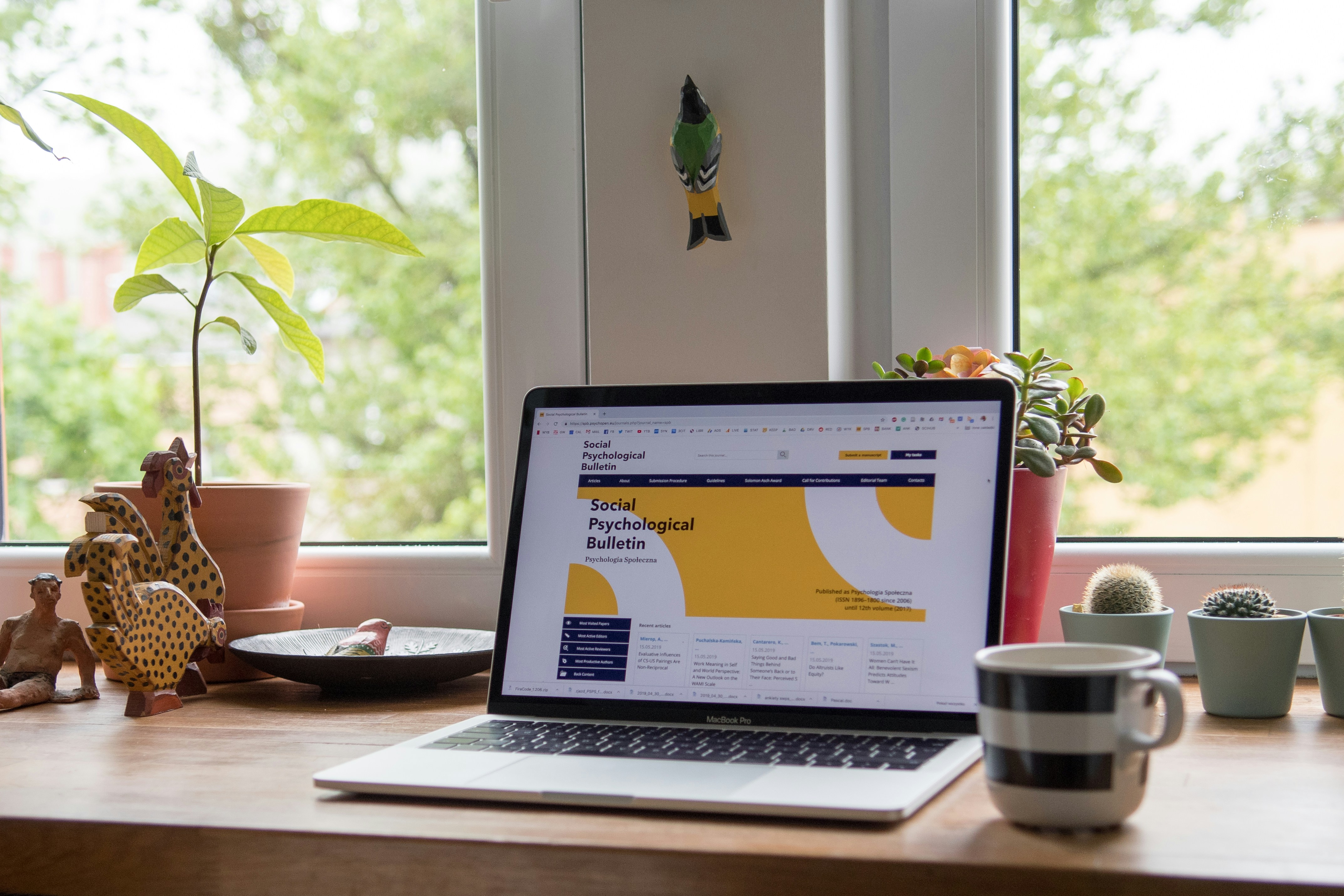 Laptop displaying a website on a desk beside a window